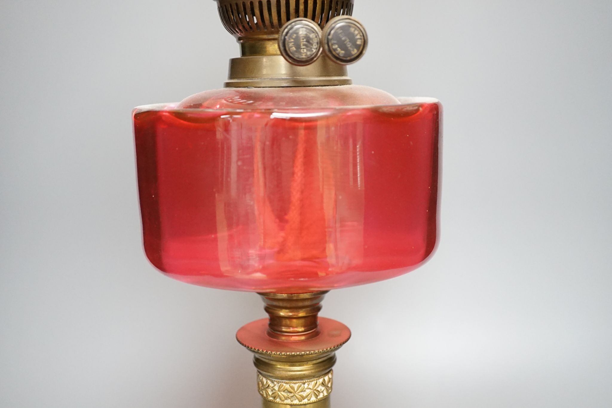 A brass and cranberry glass oil lamp with shade and chimney, total height 66cm